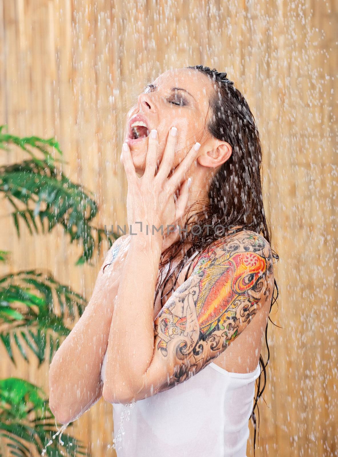 young woman in white shirt with tattoo on her hand under shower