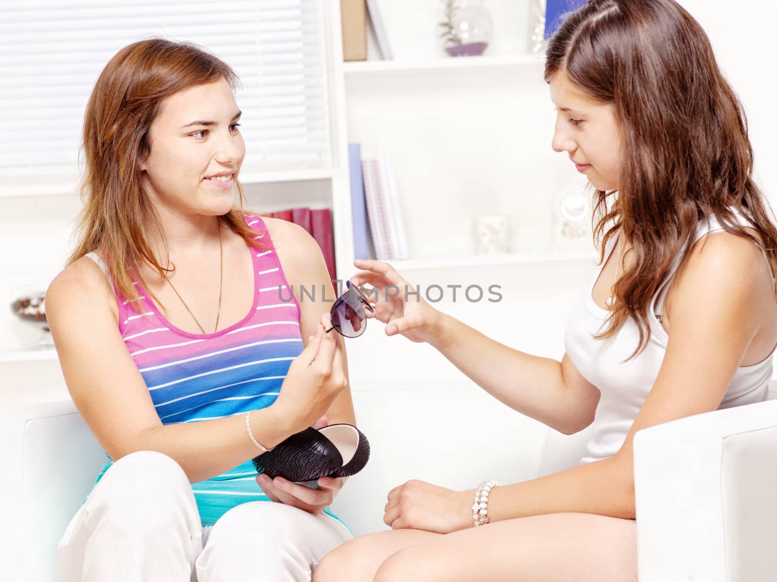 Teenage girl shows sunglasses to her friend