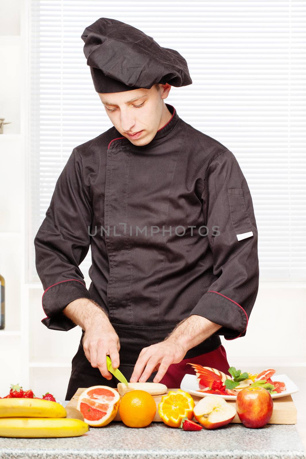 chef in black uniform cutting fruit on board in kitchen