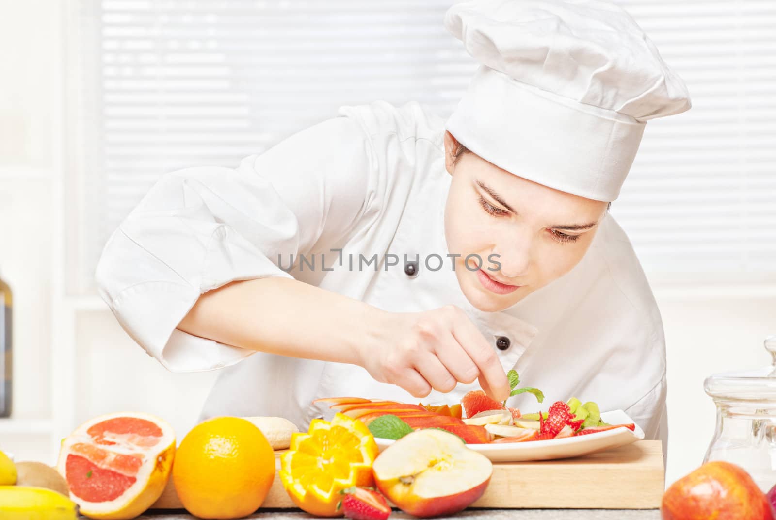 pretty young chef decorating delicious fruit plate