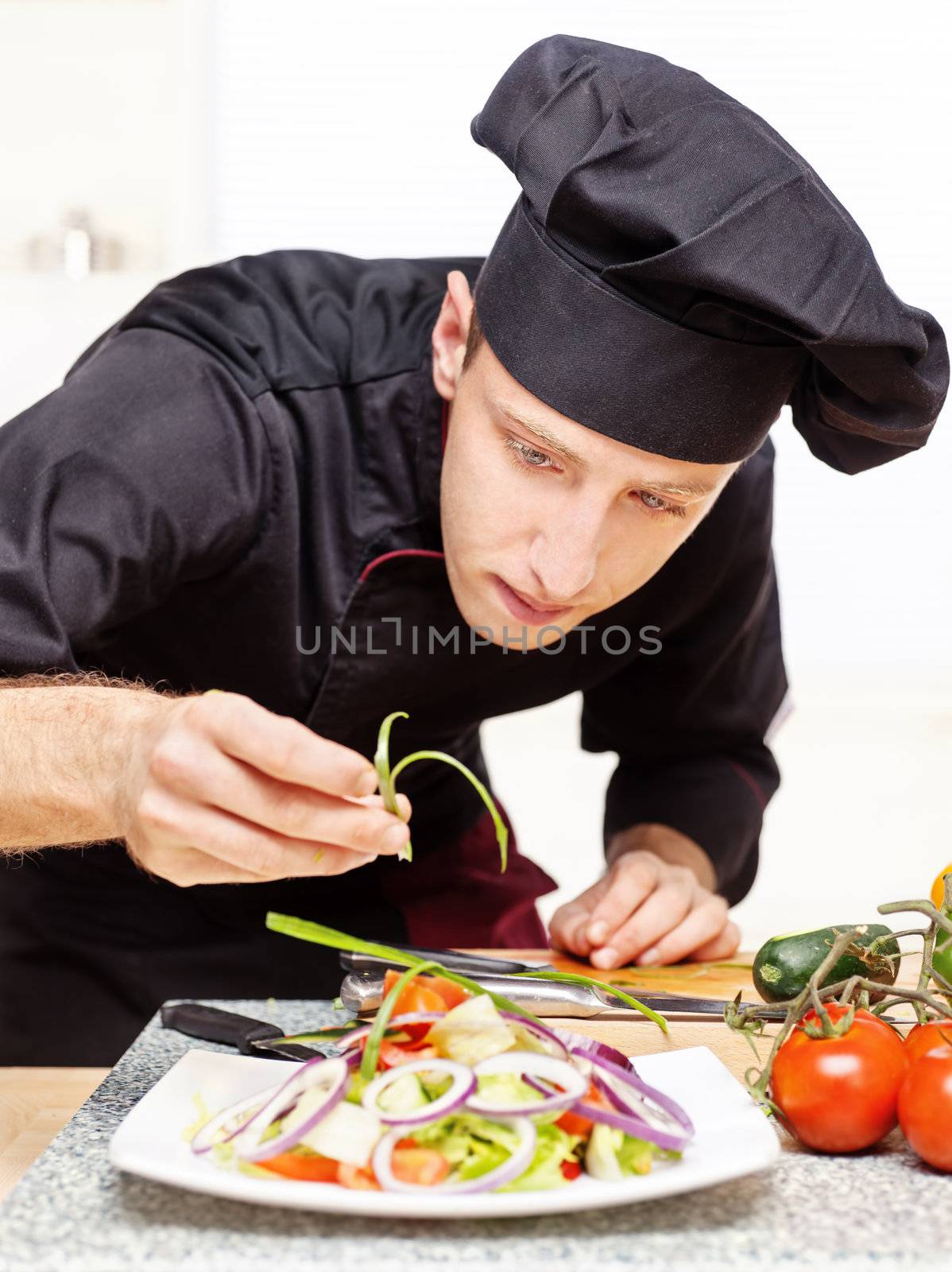 chef in black uniform decorating delicious salad plate