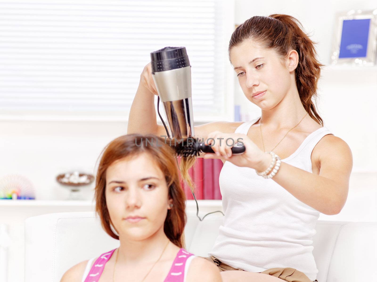 Teenage girl dries hair to her friends at home