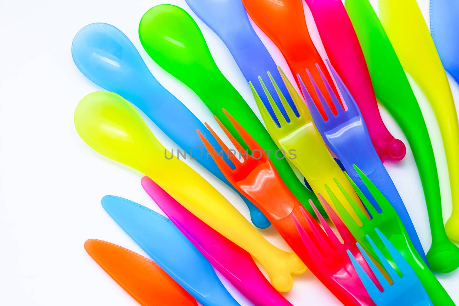 Multi colored plastic cutlery on a white background