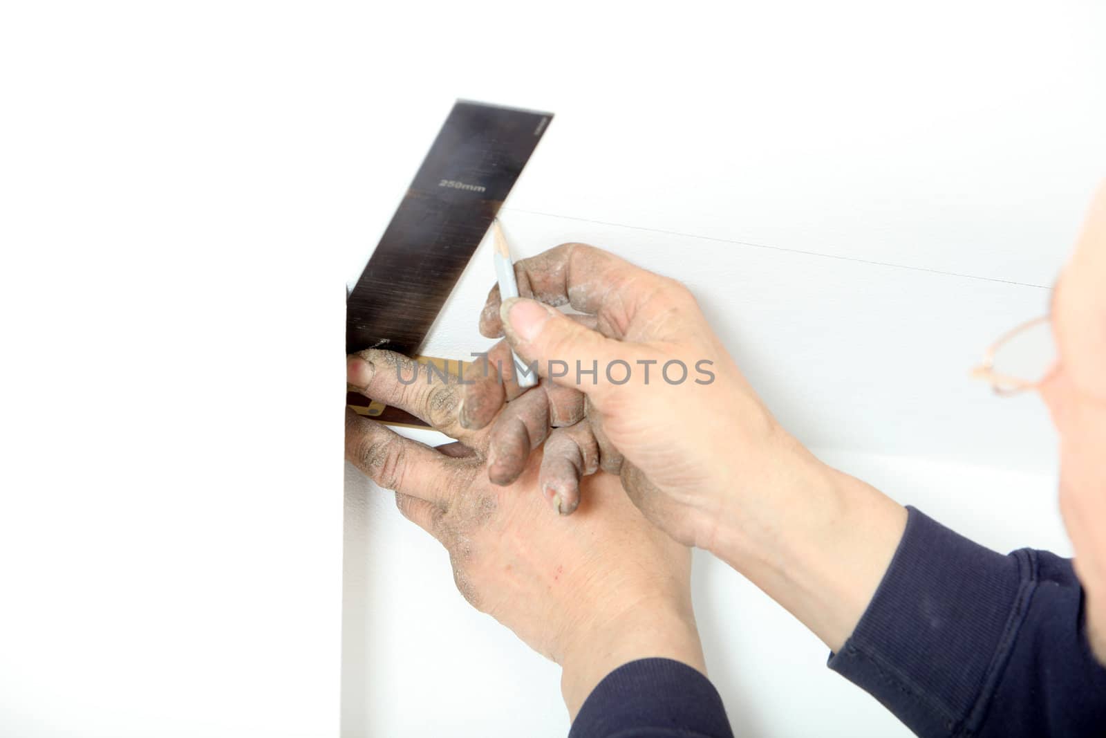 A man uses a right-angled square to measure and mark a postion on the ceiling relative to a corner of the building