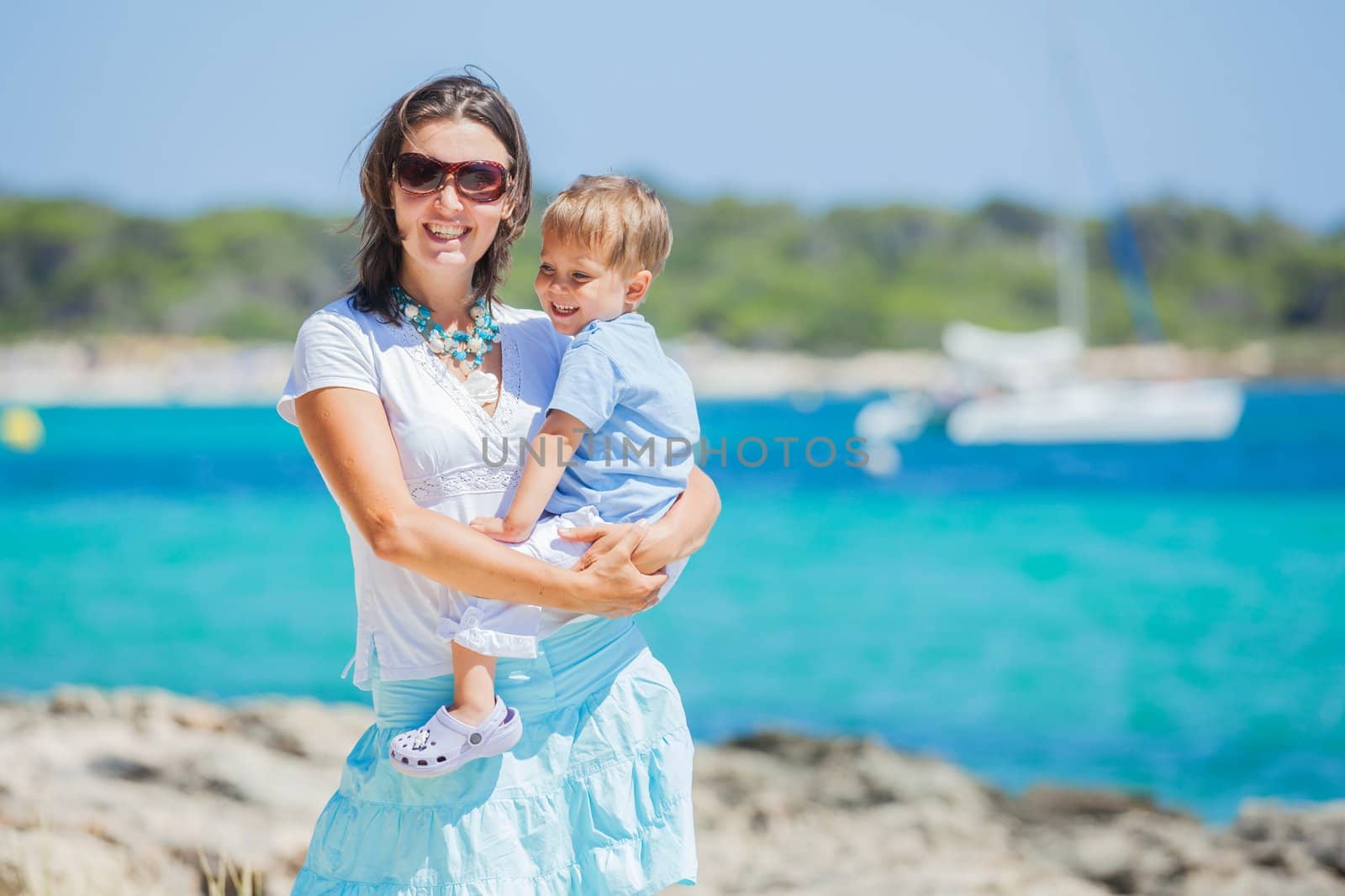 Young beautiful woman wis her son walking along tropical beach