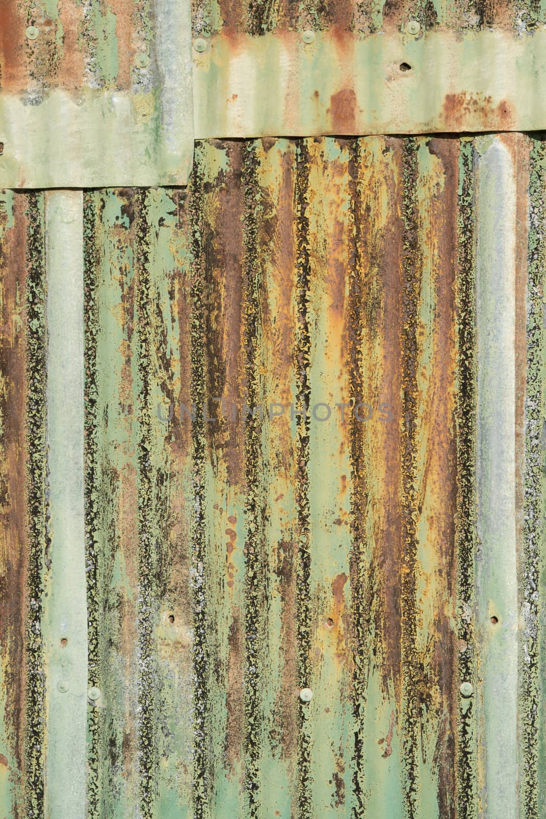 A background of metal sheets overlapping with various shades of color paint and rust.