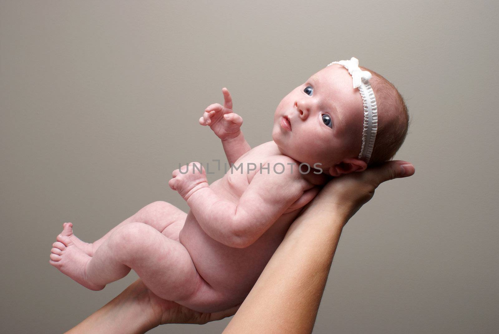 A mother holds her new born baby in the air to capture her innocent beauty.