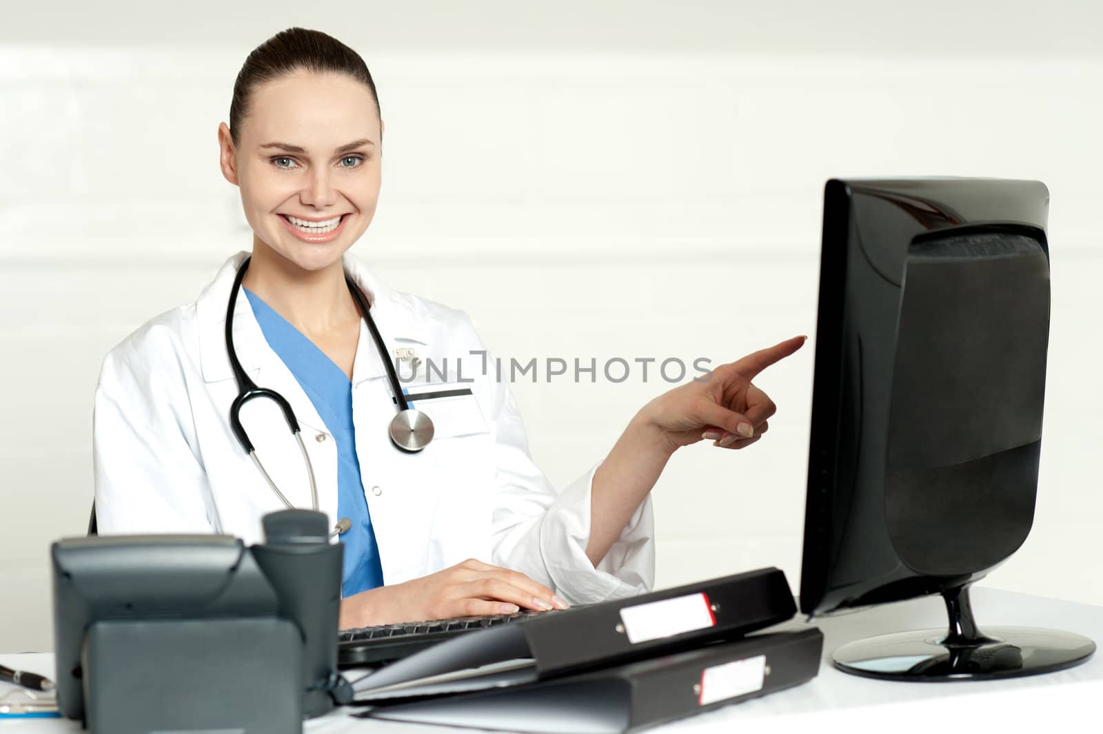 Female professional pointing at lcd screen with stethoscope around her neck