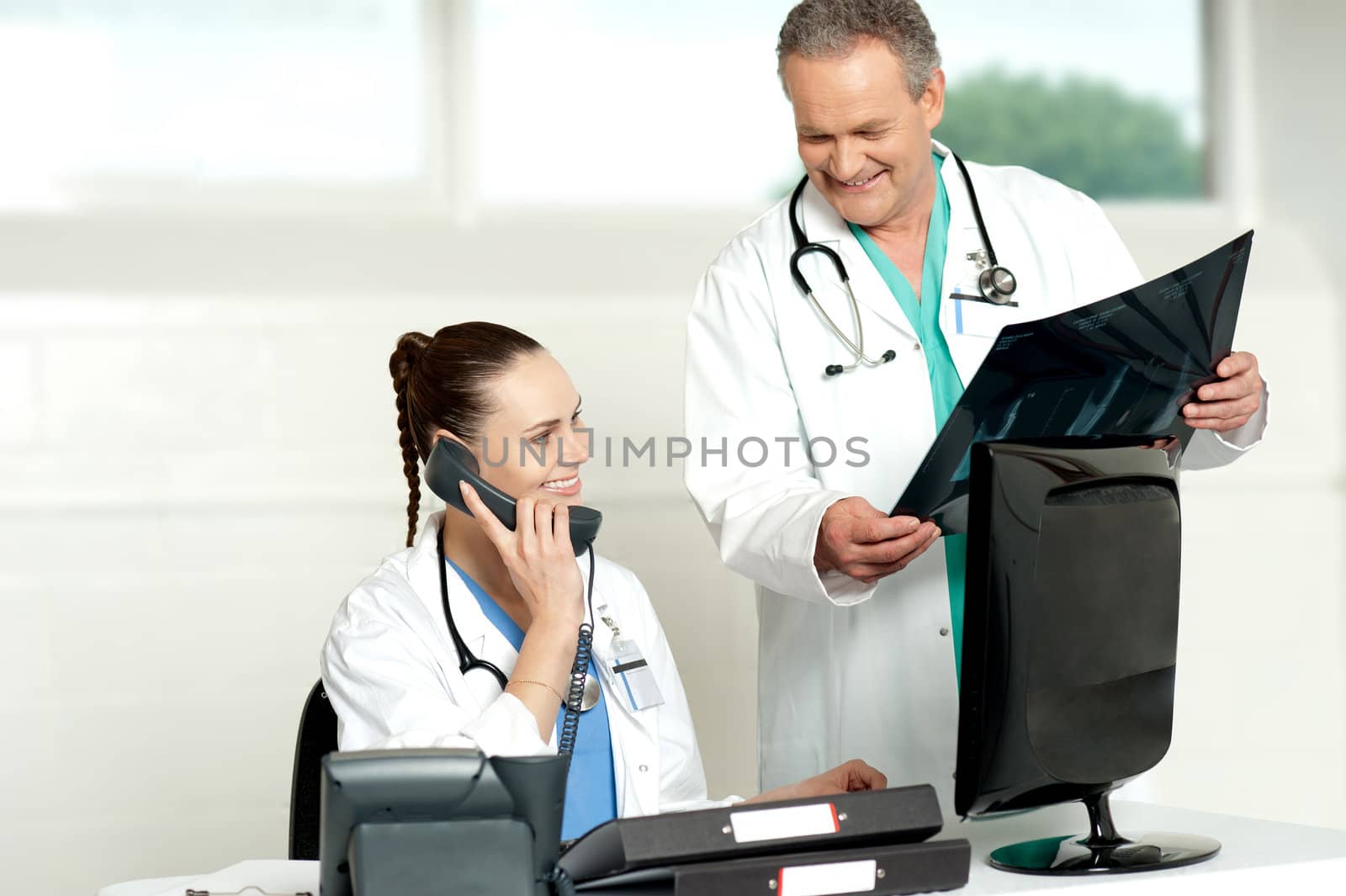 Doctors team in a lab discussing x-ray report. Woman on a call and man showing x-ray report to woman