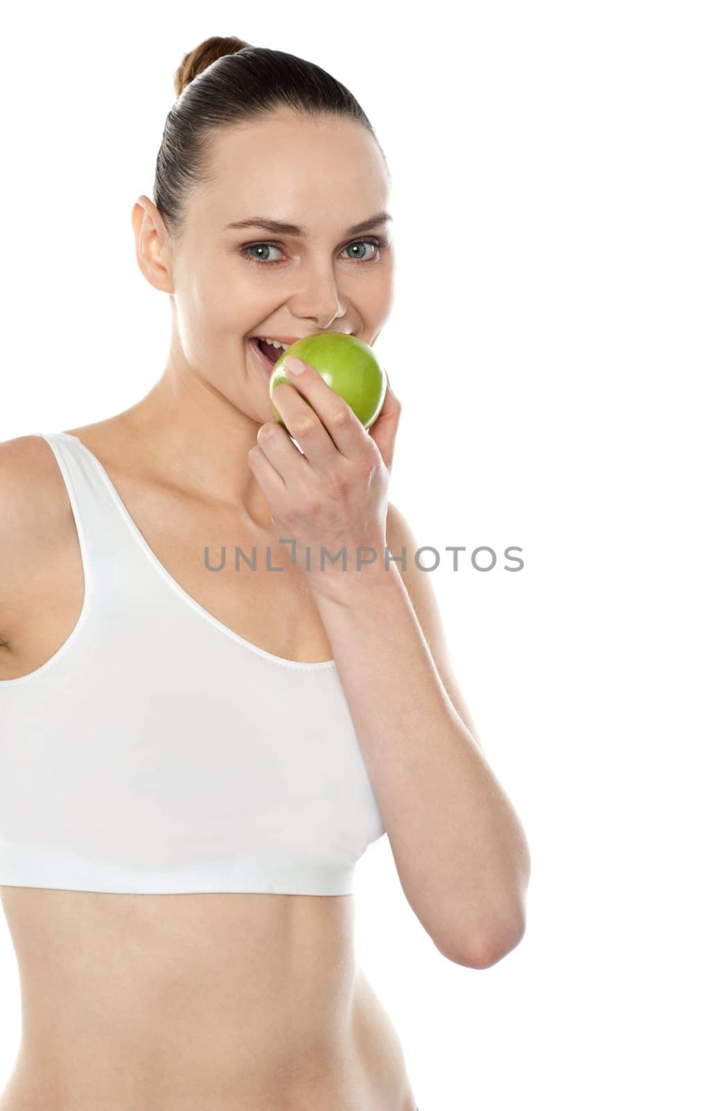 Pretty fit trendy woman eating fresh green apple isolated over white