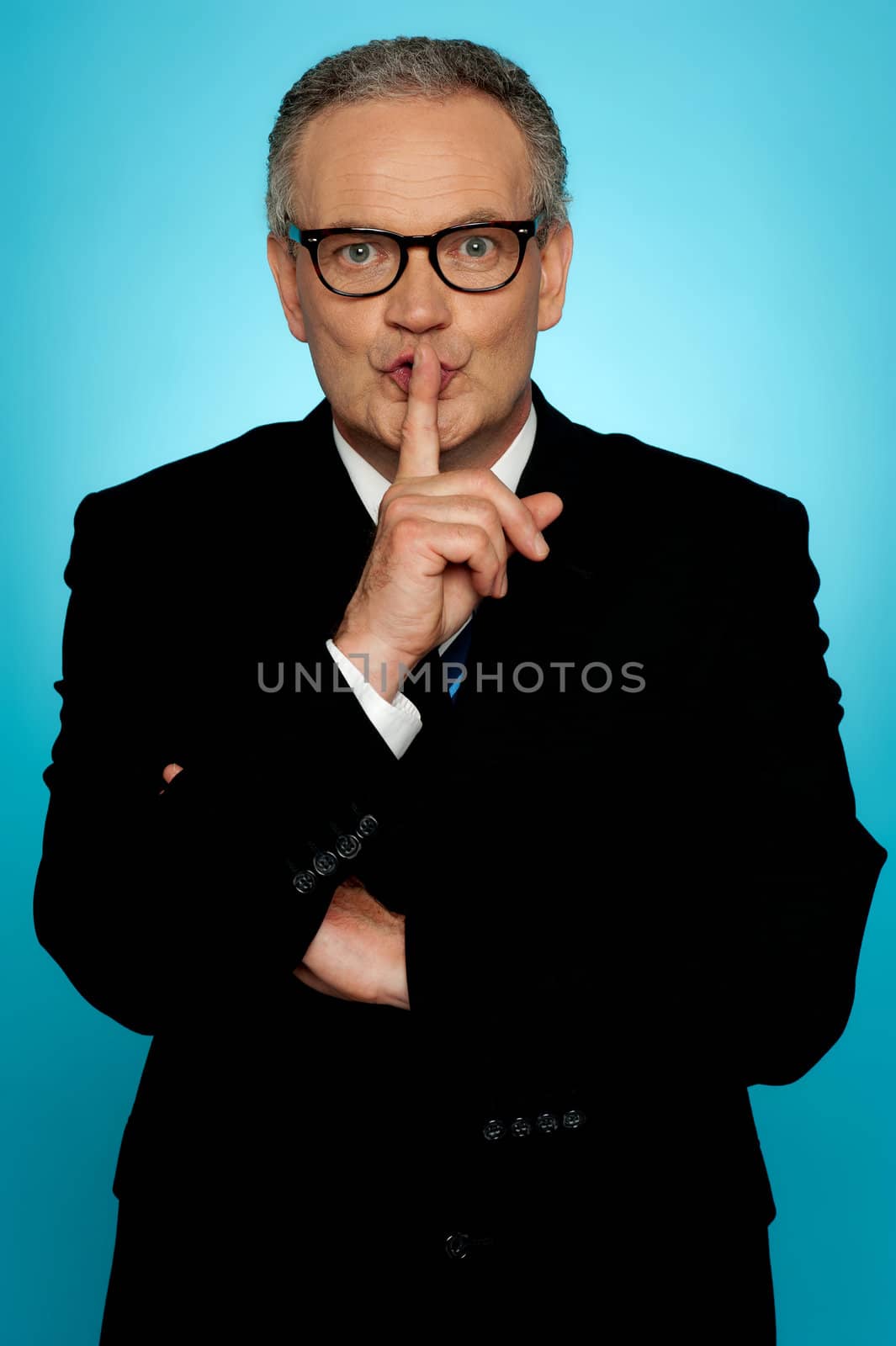 Silence please, businessman looking at you with finger on his lips