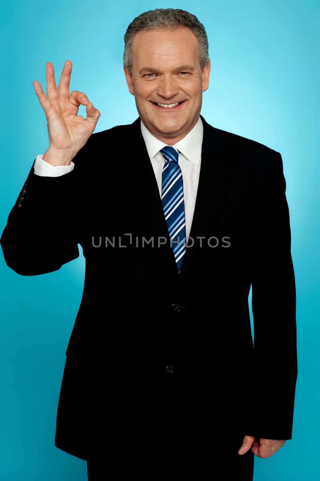 Handsome portrait of experienced businessman showing okay sign over gradient background