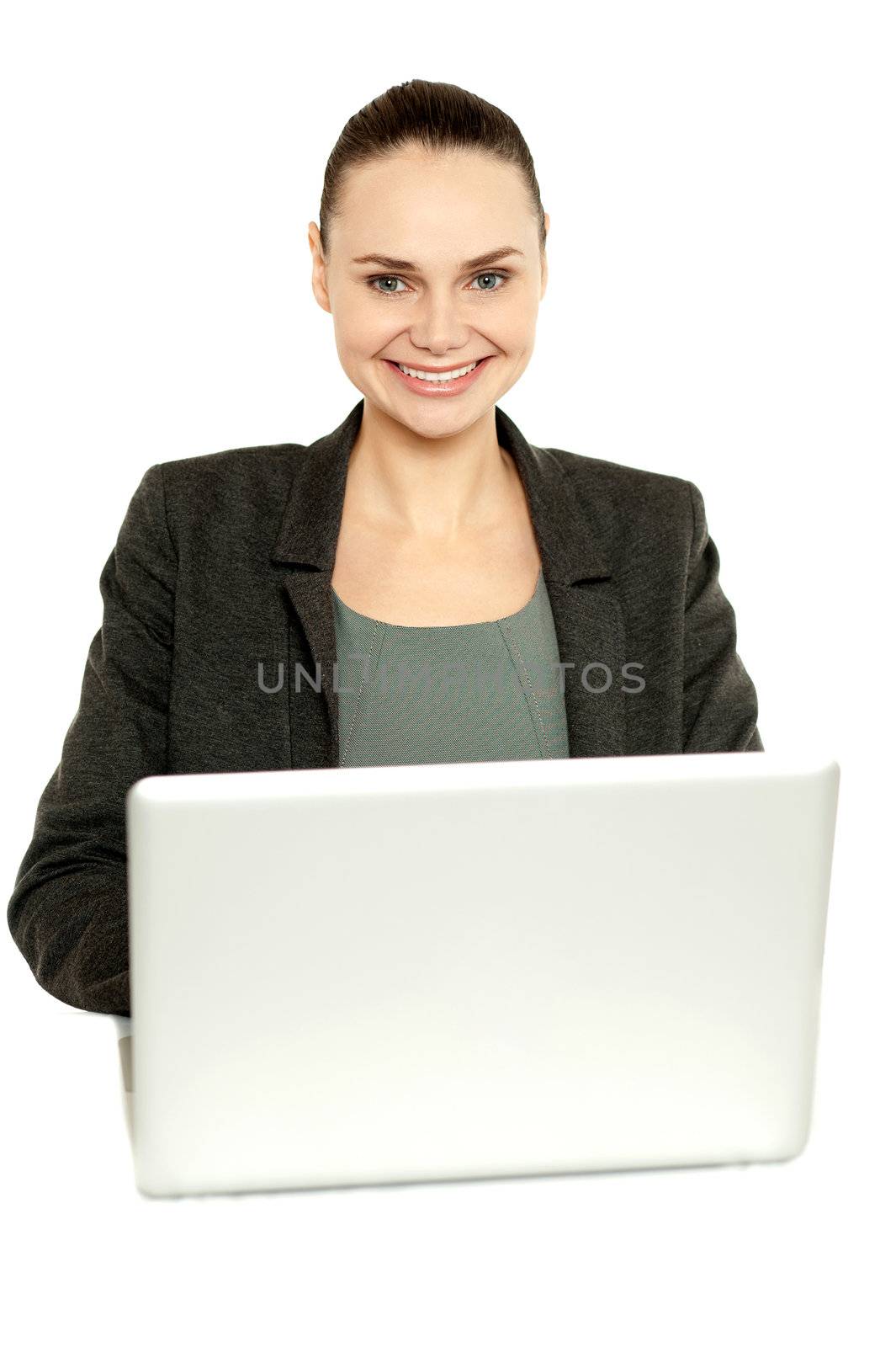 Attractive corporate female working on laptop and smiling at camera