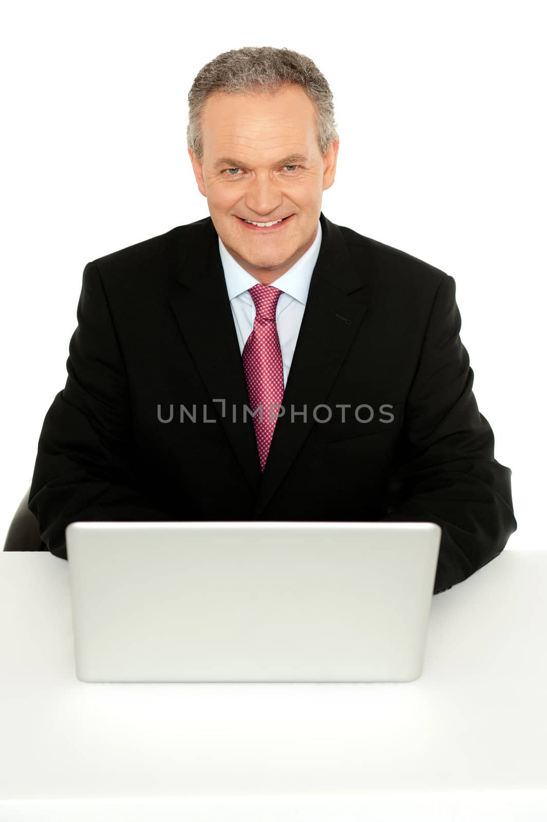Portrait of successful senior businessman sitting with laptop in front of him