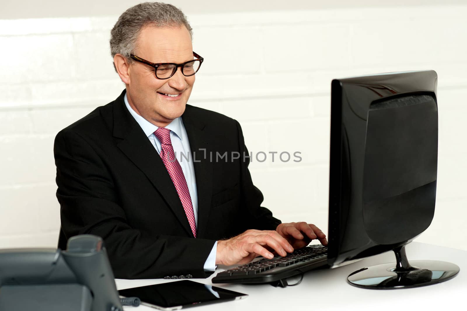 Casual businessman working in office sitting at desk typing on keyboard looking at computer screen