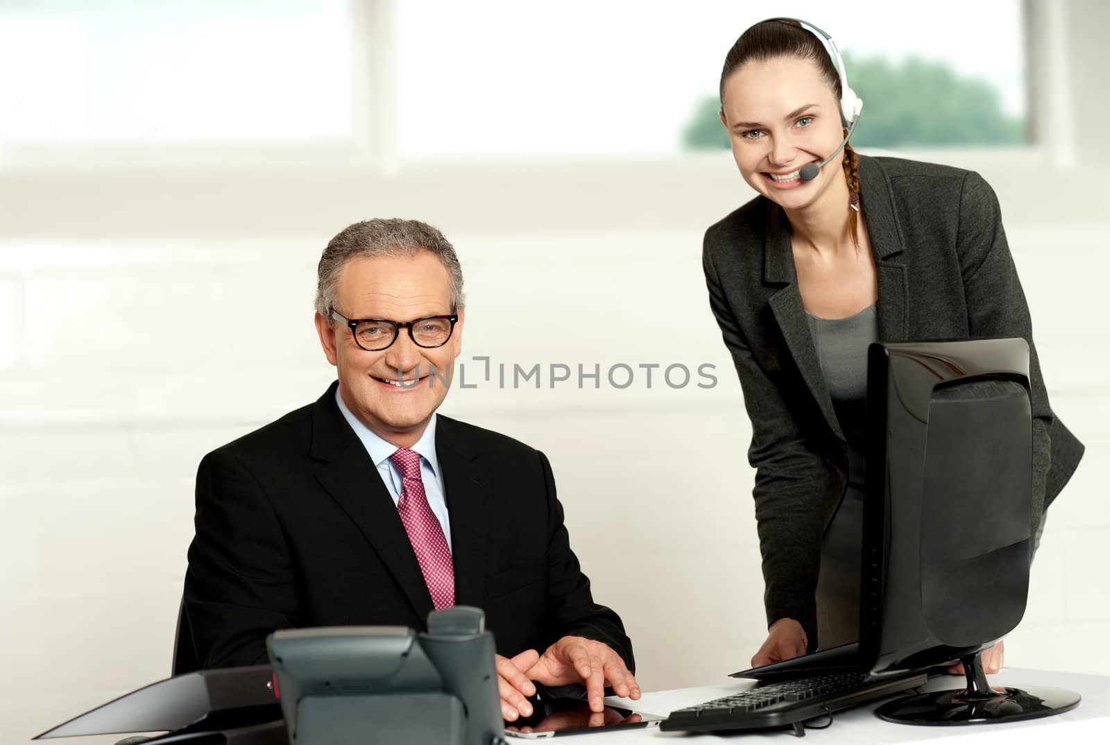 Successful team of senior man and young woman looking at camera