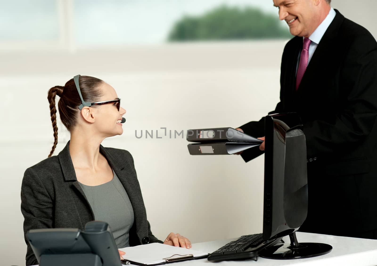 Business team of two working in office. Woman sitting in chair while man presenting files to her
