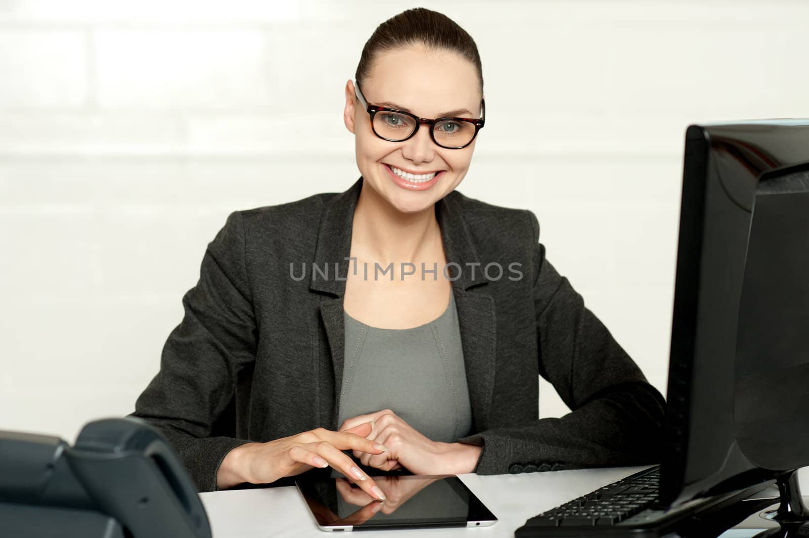 Pretty manager working on wireless tablet device sitting in her office