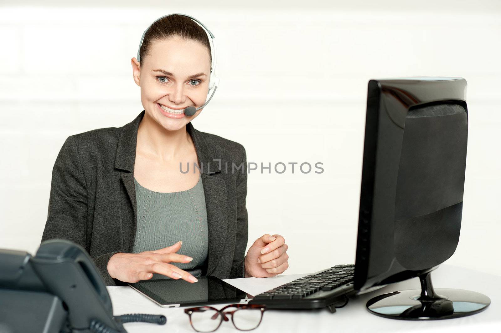 Customer care executive using tablet pc wearing headsets and looking at camera