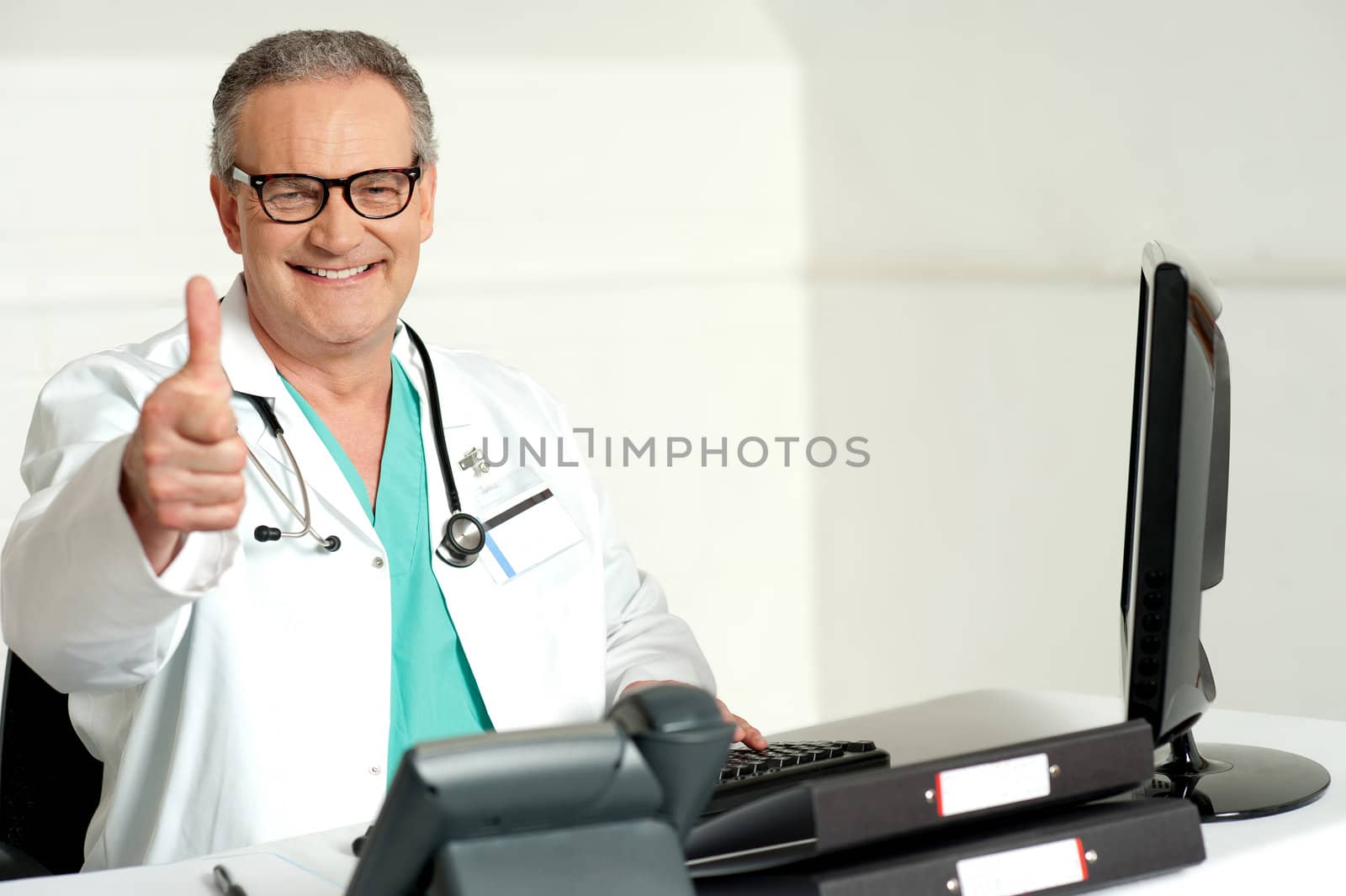 Smiling doctor gesturing thumbs up to camera while working in his clinic