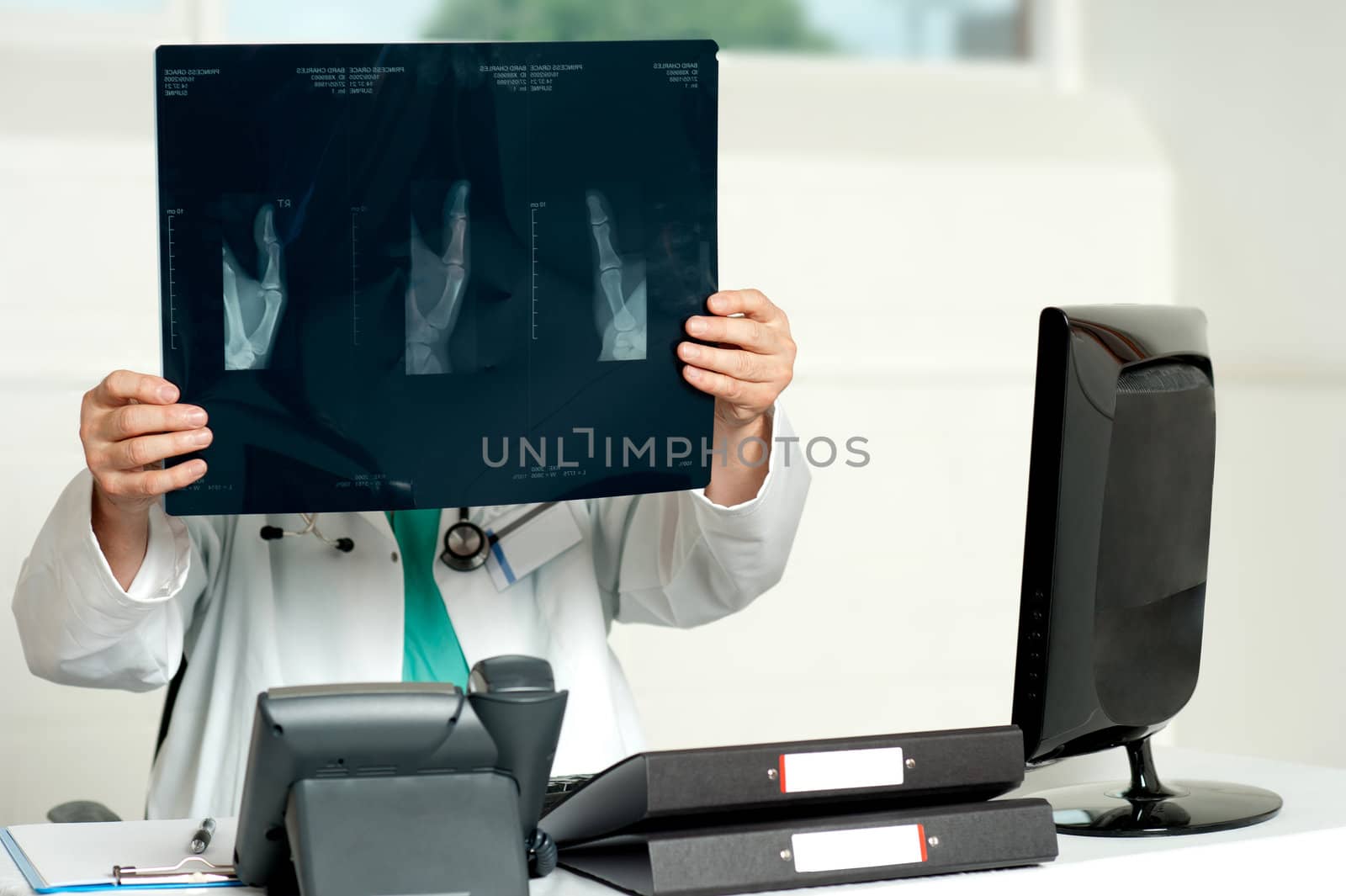 Male surgeon holding x-ray which hid his face