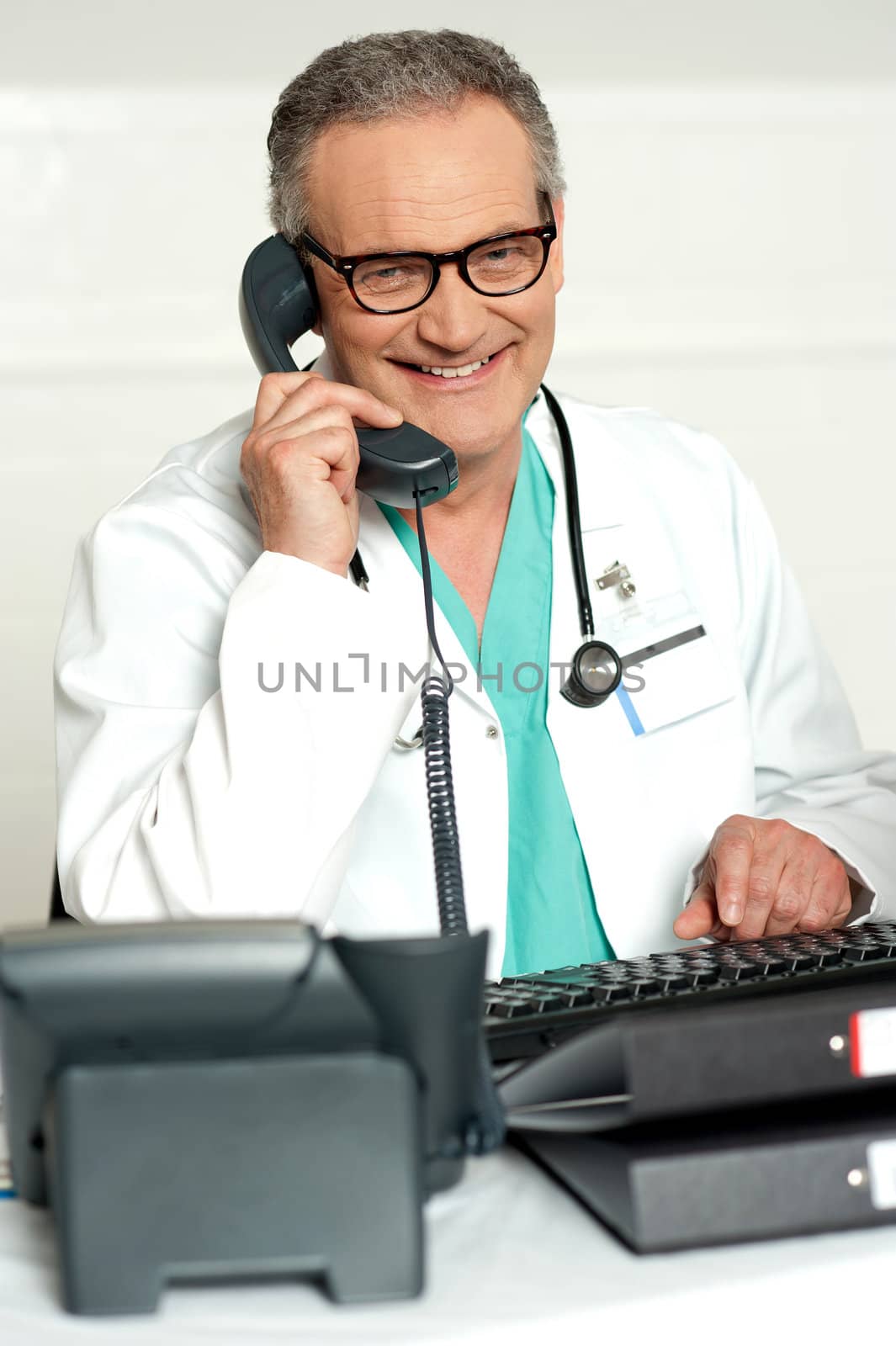 Matured physician communicating on phone sitting on chair in his lab
