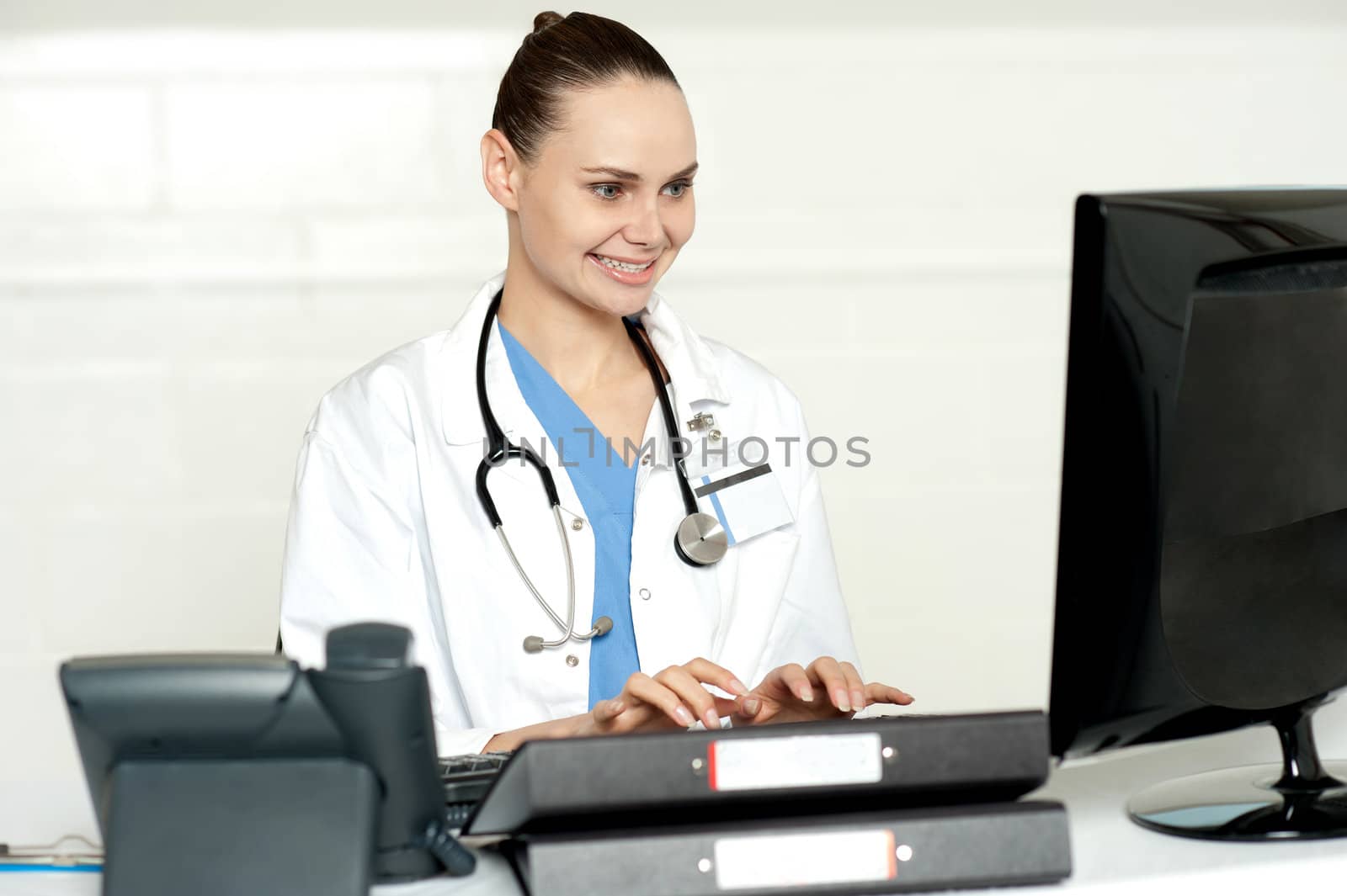 Medical professional working on computer looking at lcd screen while typing on keyboard