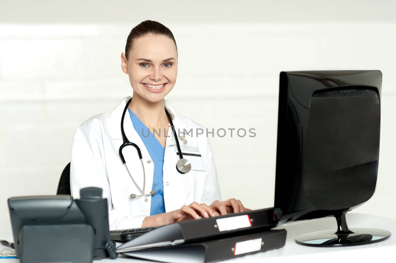 Smiling female doctor working on computer in her chamber