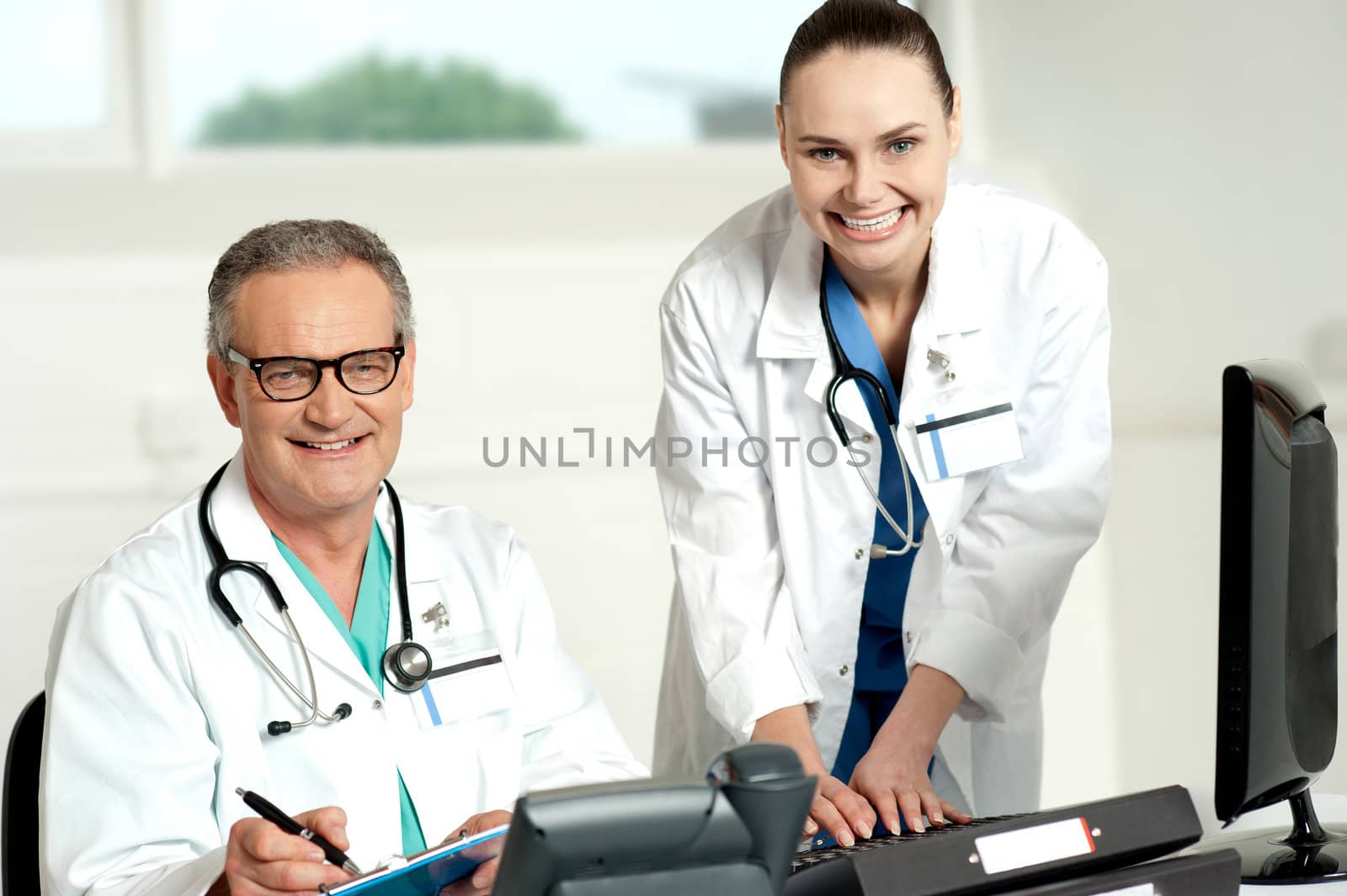 Doctors team. Female assistant typing on keyboard and man writing on clipboard