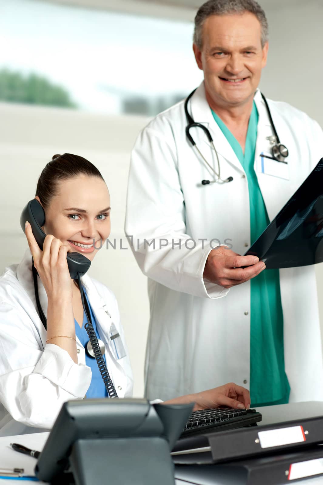 Two medical representatives. Woman attending call and man holding x-ray report