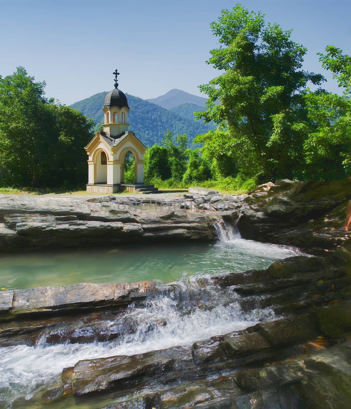 The chapel in the mountains on the banks of the waterfall