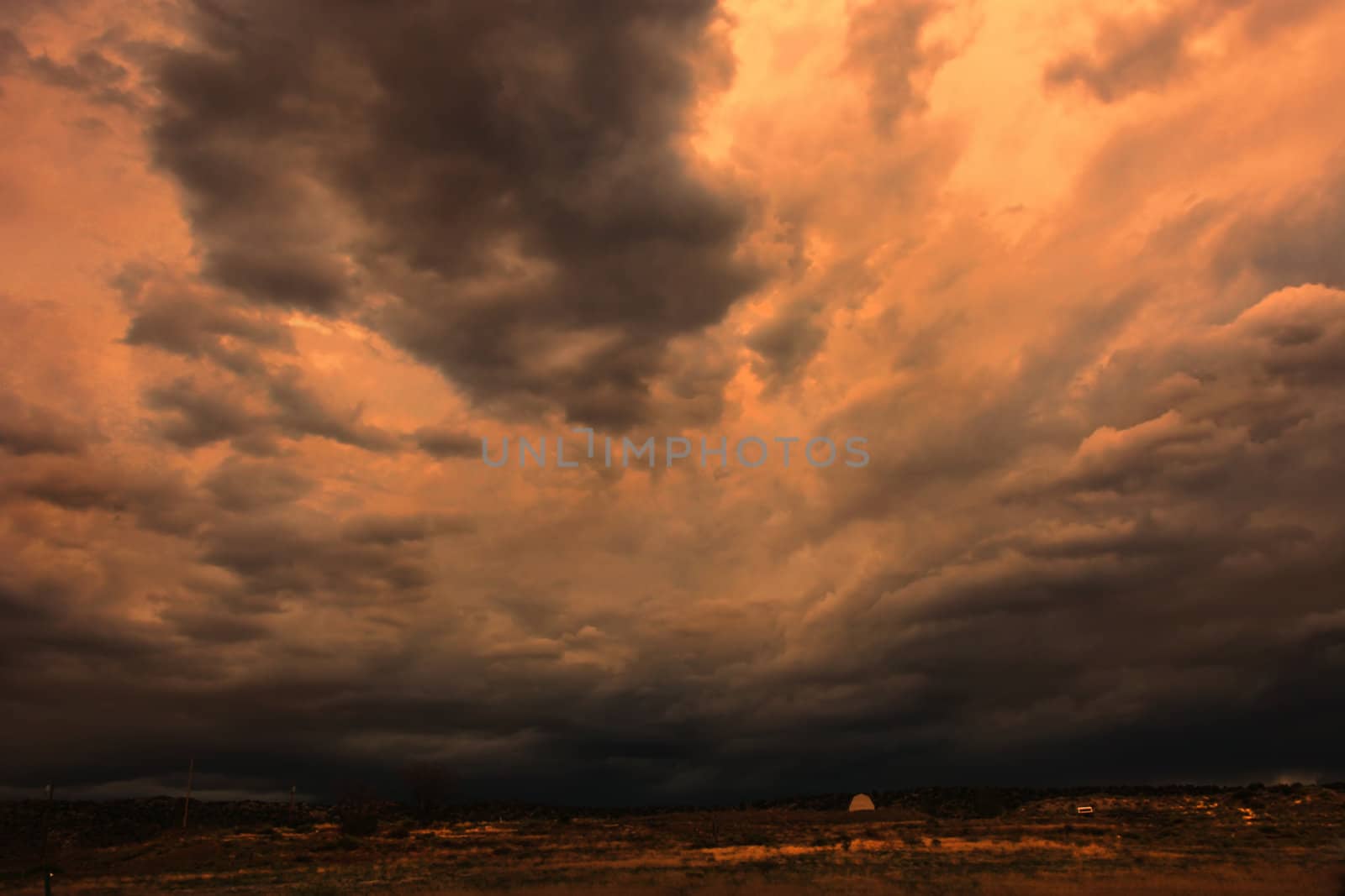 Ominous thunderheads rolling over landscape at sunset