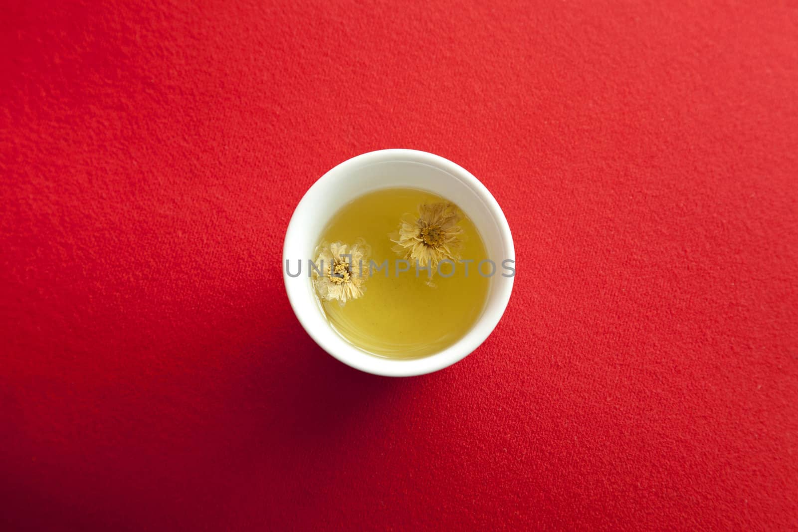 a cup of warm Chrysanthemum tea on red fabric background