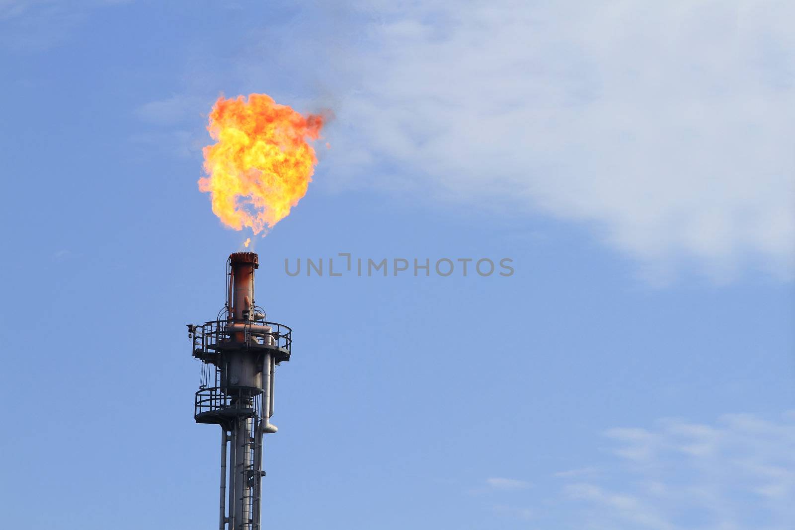 Burning oil flare on a blue sky by rufous