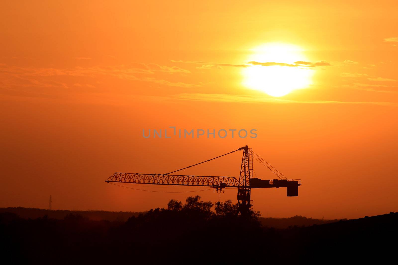 Industrial landscape with silhouettes of cranes on the sunset background