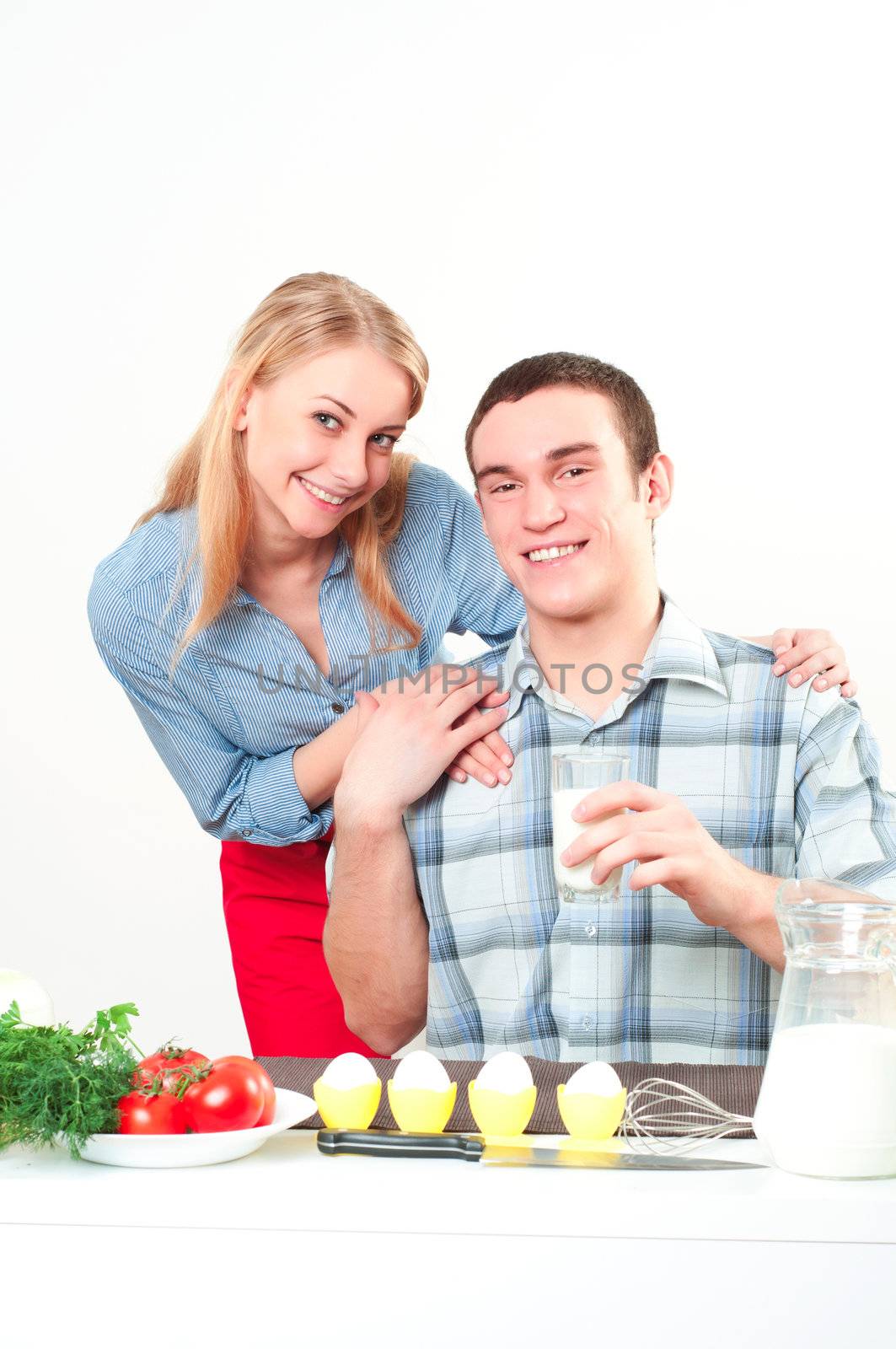 woman hugging a man's shoulders, he's holding a glass of milk