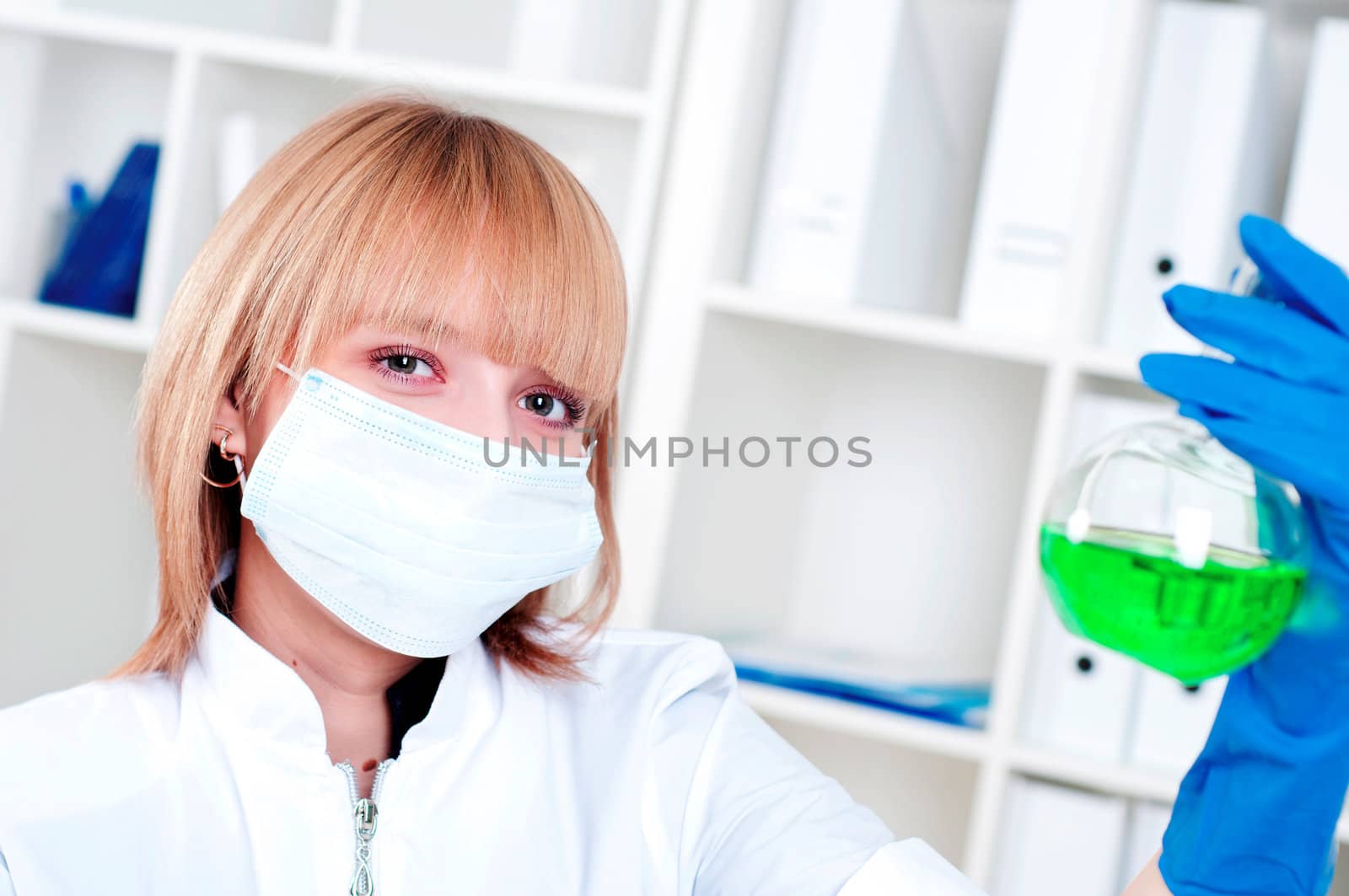 Woman chemist in protective mask holds a test tube with green liquid