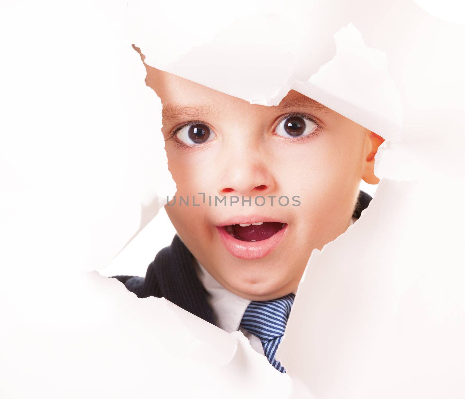 Yawning kid looks up through a hole in white paper