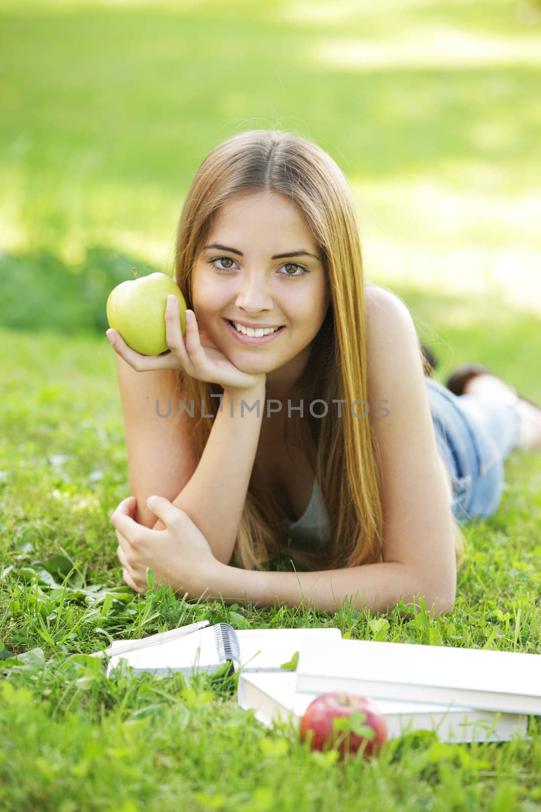 Young smiling woman outdoors holding an apple