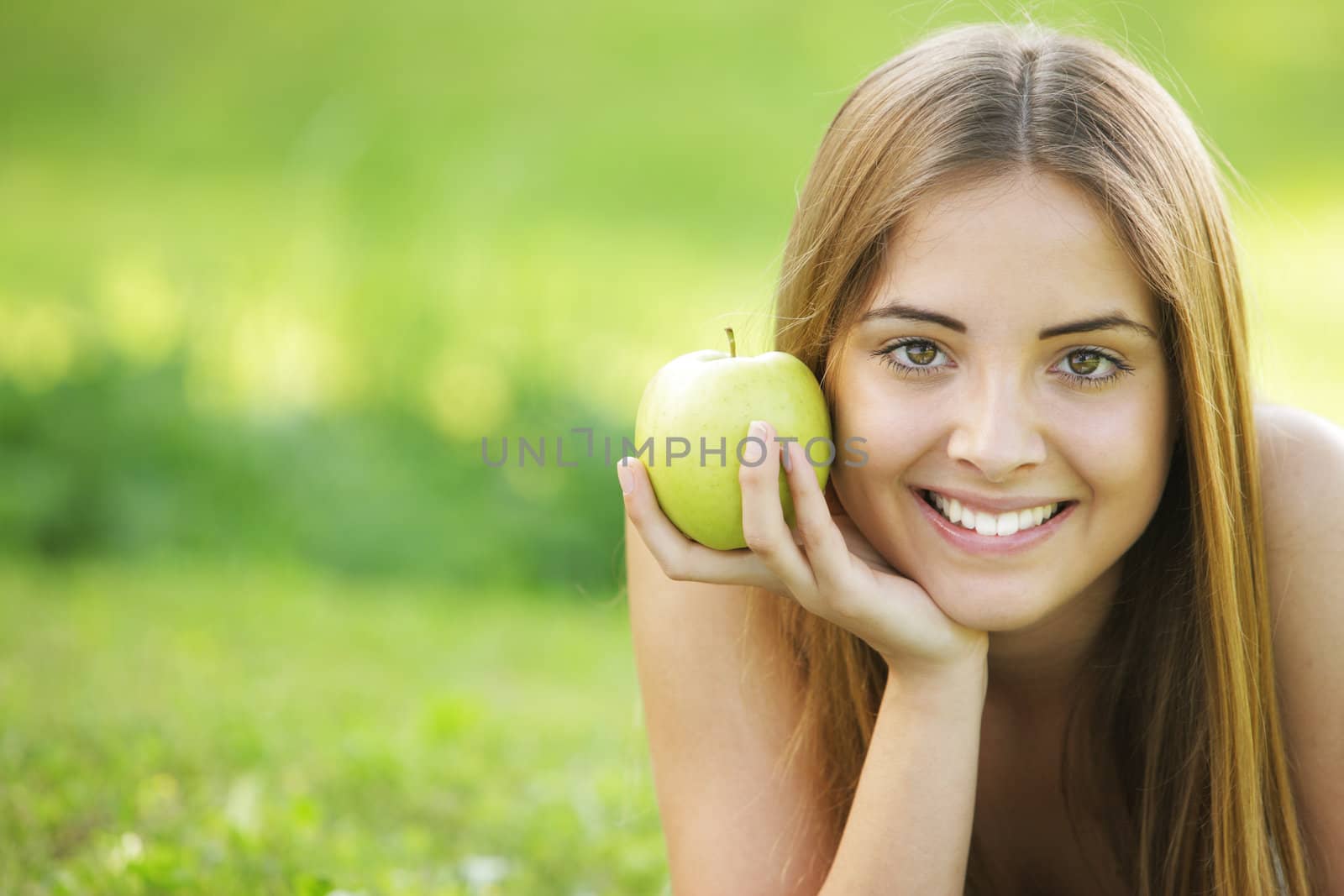 Young smiling woman outdoors holding an apple