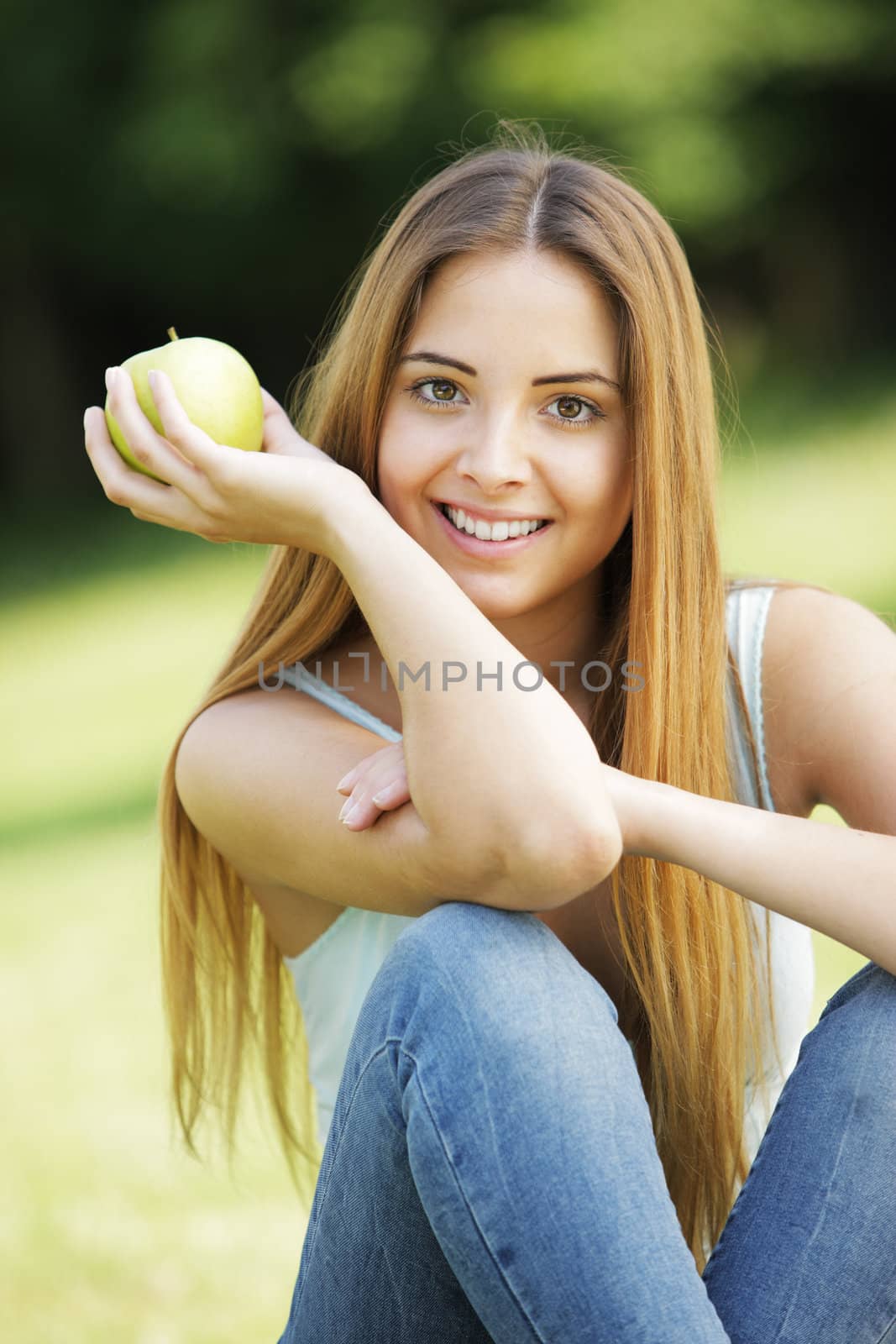 Young smiling woman outdoors holding an apple