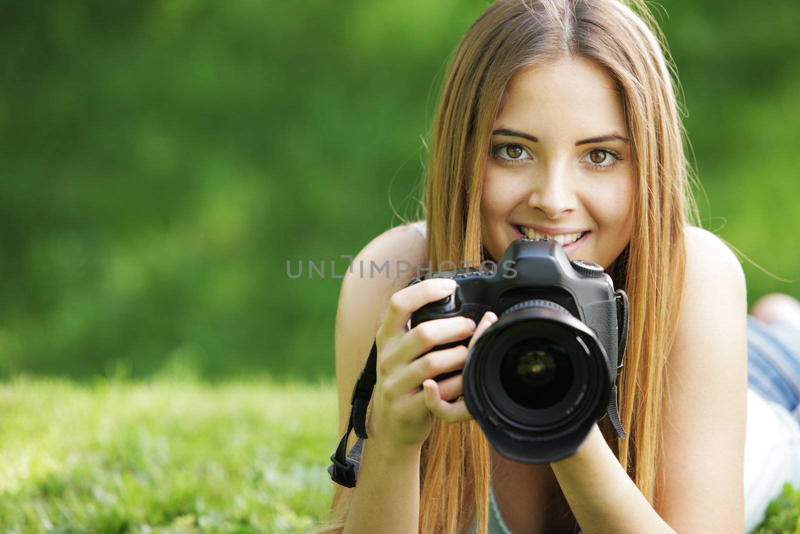 Portrait of beautiful smiling blonde girl , making photos at summer green park.