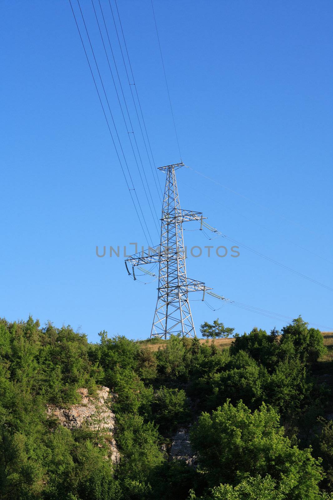 Large electricity pylon on the hill against blue sky