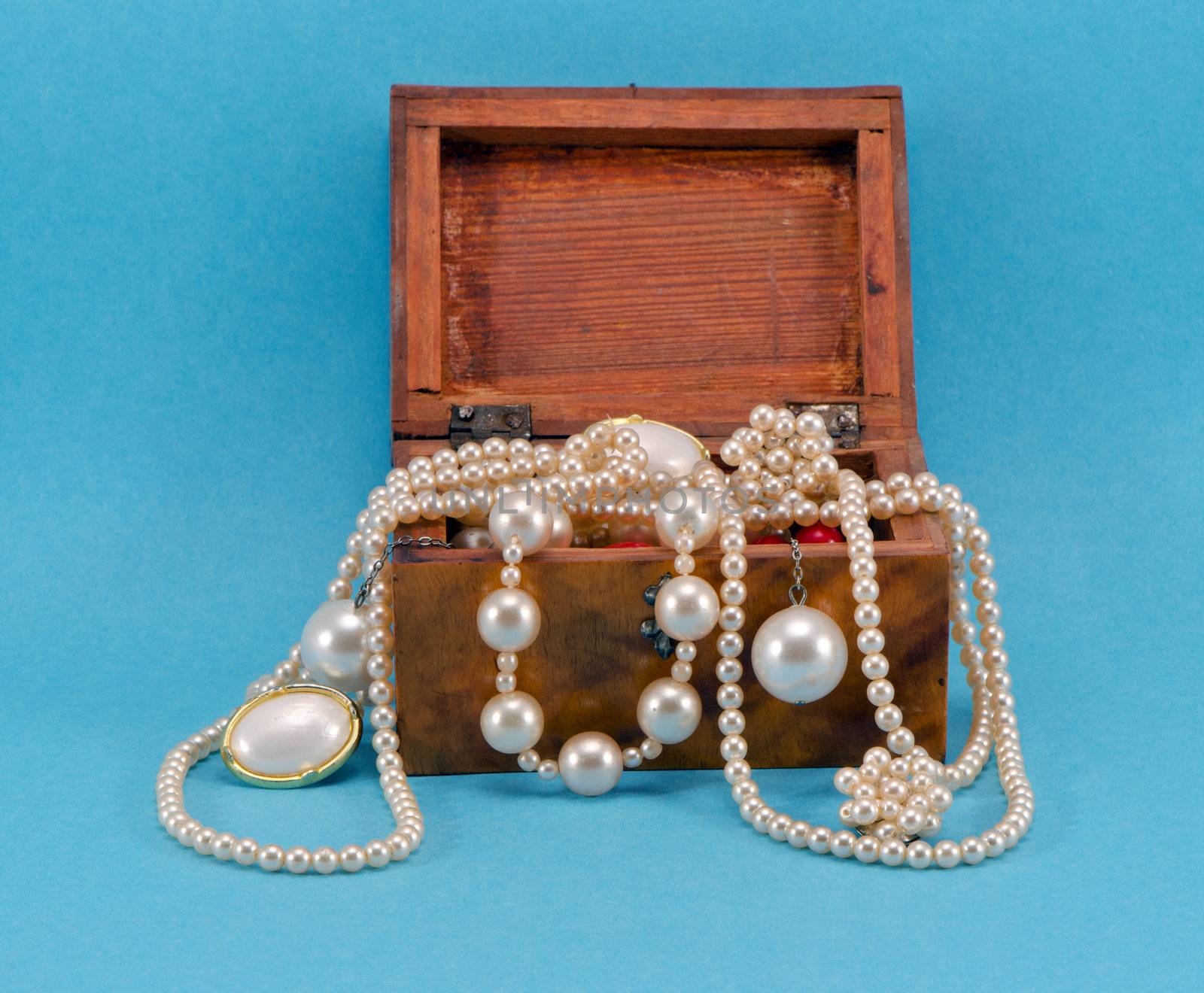 Pearl jewelry beads necklace earring in retro wooden box on blue background