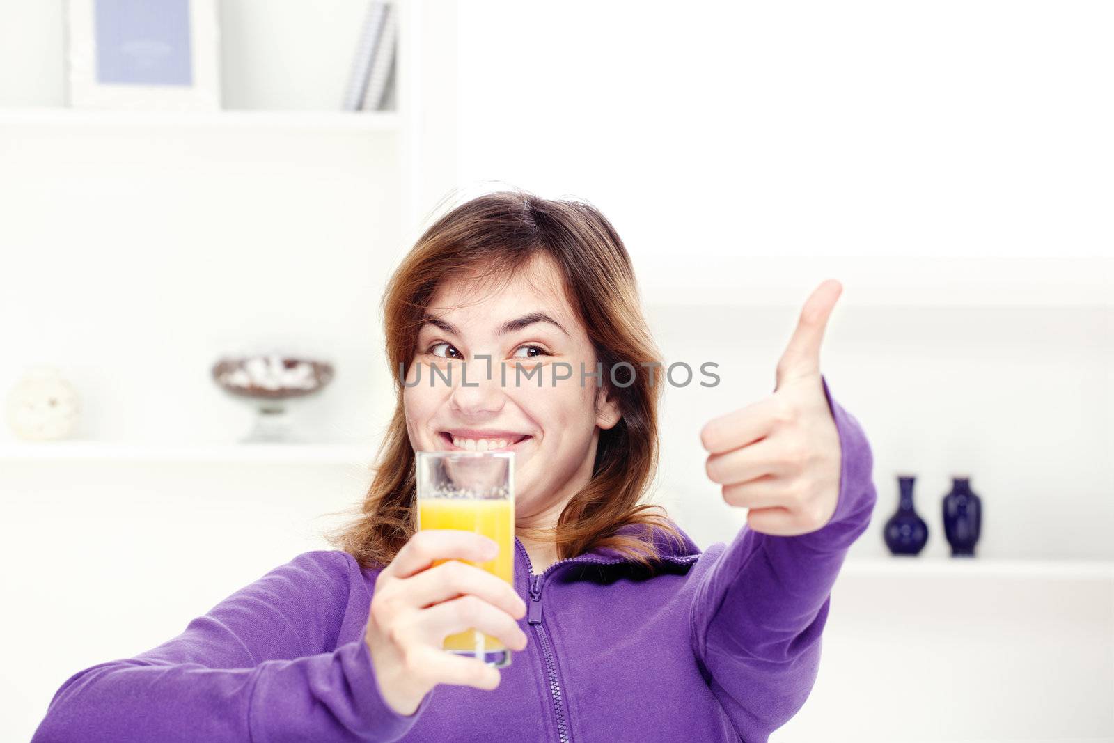 happy teenage girl drinks orange juice at home