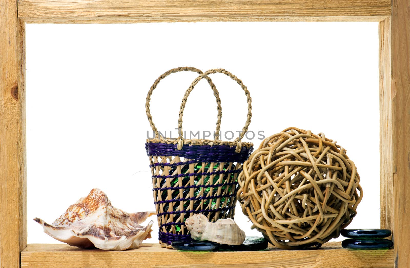 Wicker, green pieces of glass and sea shells inside rough wooden frame on white background