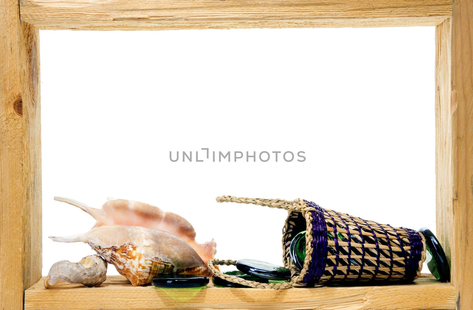 Wicker, green pieces of glass and sea shells inside rough wooden frame on white background
