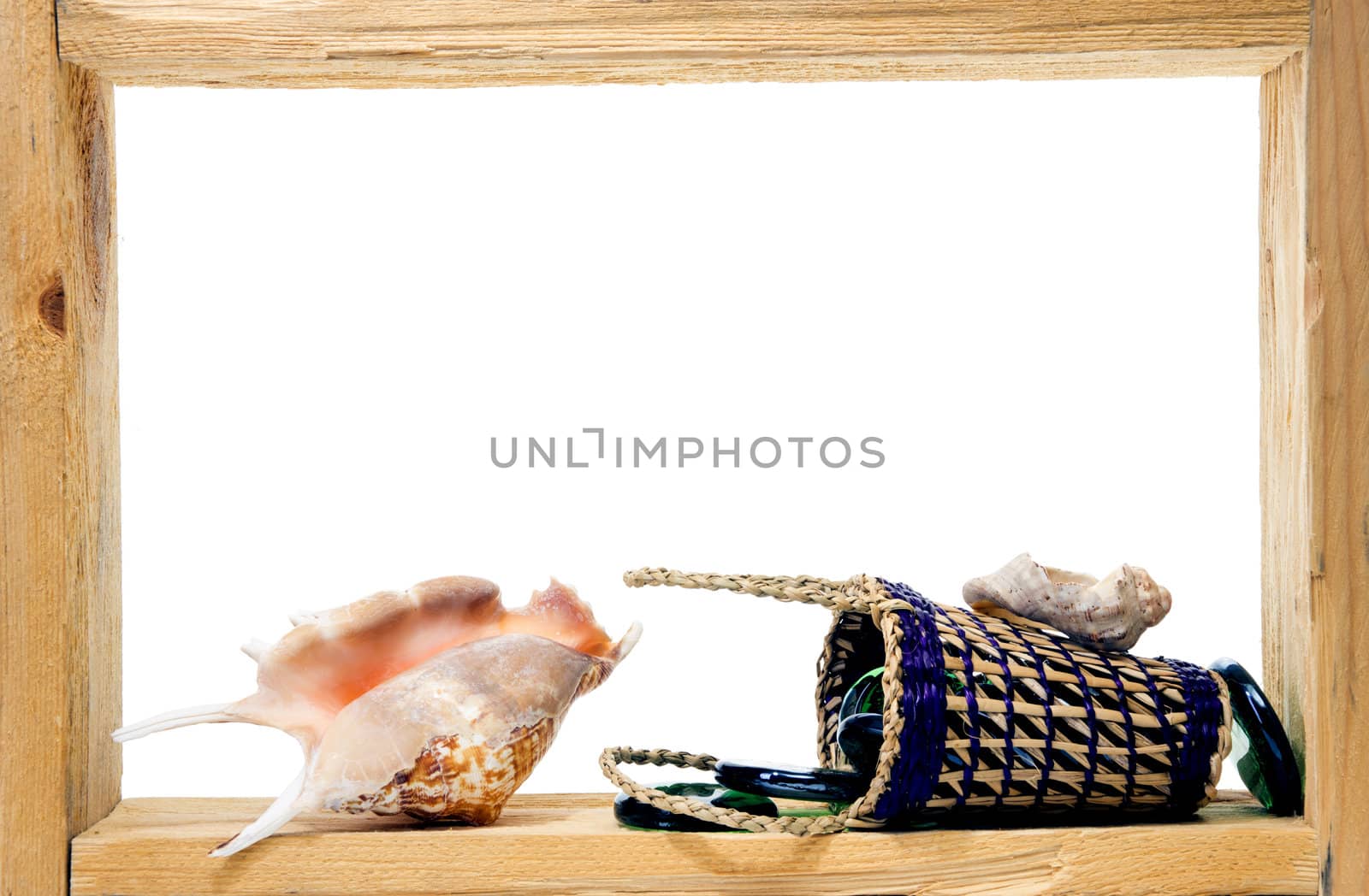 Wicker, green pieces of glass and sea shells inside rough wooden frame on white background