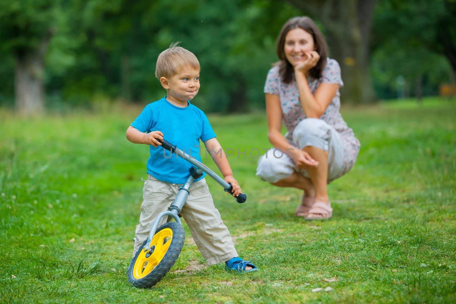 Portrait of little boy on a bicycle and his mother in the summer park