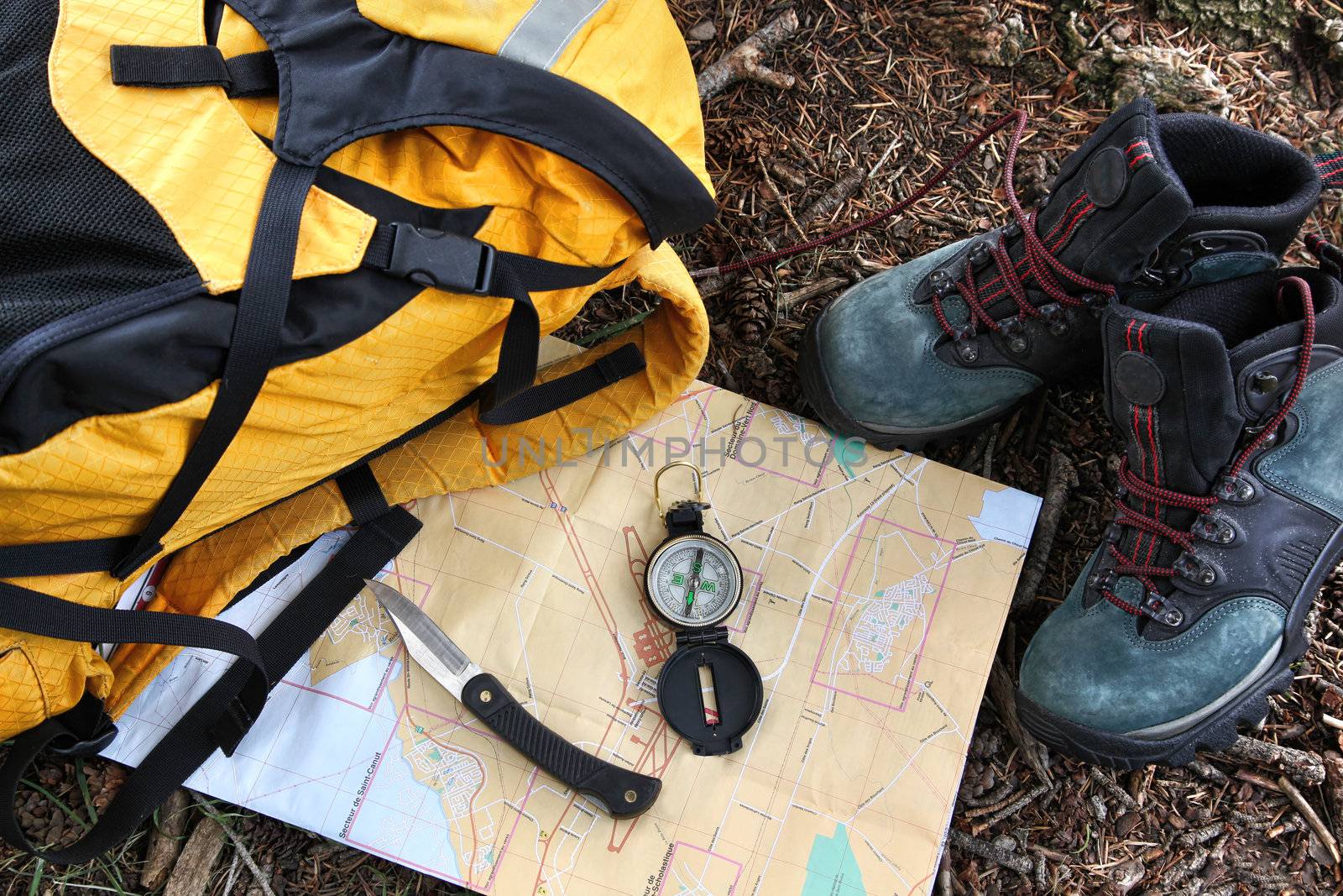 Hiking shoes on map with compass and backpack